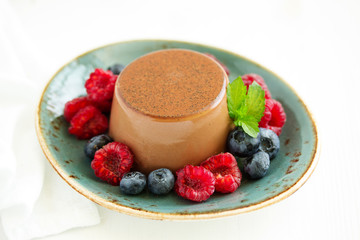 Delicious home-made chocolate dessert Panna cotta. Cream-caramel, caramel custard, with raspberries and blueberries.