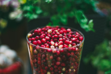 Close-up view of glass with fresh raw red cranberries (oxycoccus palustris) just recently harvested for Thanksgiving day; defocused background; shallow depth of field