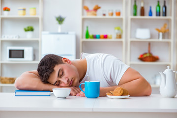 Obraz na płótnie Canvas Man falling asleep during his breakfast after overtime work