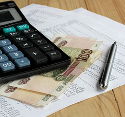 Calculator and Russian money on sheets of paper with numbers.