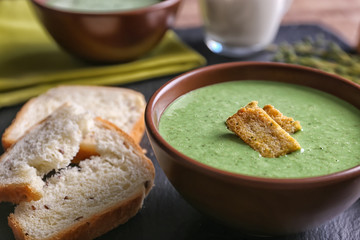 Puree from green peas in bowl with rusks on table