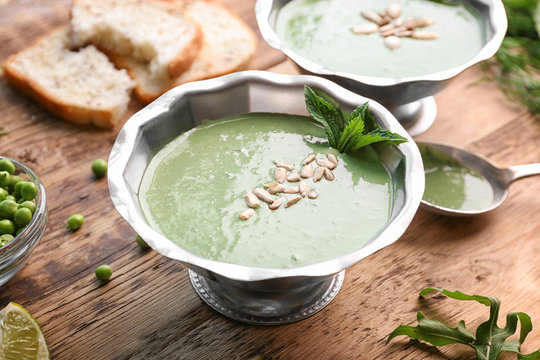 Delicious puree from green peas in bowl on wooden table