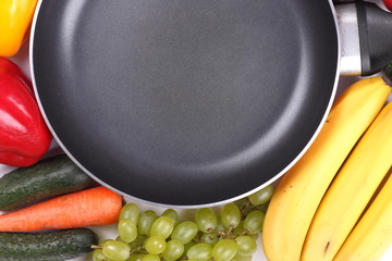 Fruits and vegetables around an empty frying pan with a place for an inscription for the designer