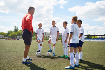 Portrait of junior football team listening to coach giving pep talk before match