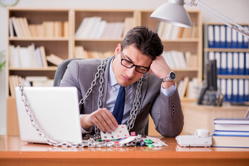 Obraz premium Young businessman addicted to online gambling cards playing in t