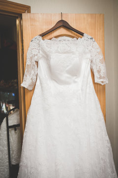 Elegant flowing wedding dress hanging from door