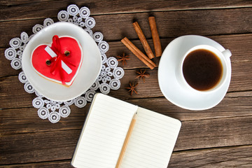 Cozy holiday. Mug coffee, heartshaped gingerbread, notepad and pencil and spices. Top view