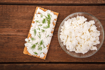 Fresh cottage cheese in a plate with dumplings with greens on a wooden background. Proper nutrition. Breakfast. Background. Top view