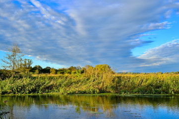 Colorful autumn landscape with a river and clouds