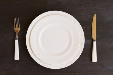 Tableware - set of plates and utencils on dark wooden background