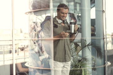 Obraz na płótnie Canvas Positive guy is holding mobile phone with smile