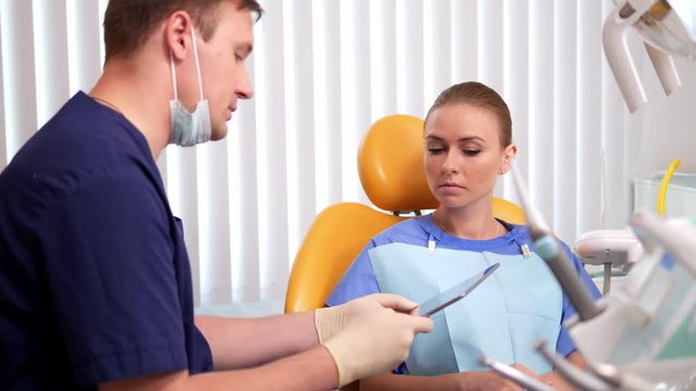 Young woman listens to the dentist's explanations for x-ray image