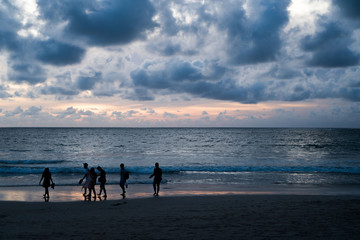 Silhouette of tourists walking on the sandy beach with beautiful sunset sky