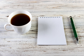 Cup of coffee with notebook on wooden desk, Top view, copy space