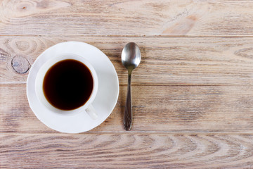 White Cup with coffee on a platter and spoon on wooden background