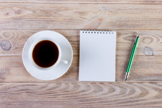 Blank notepad and pencil with cup of coffee on office wood table background. Business concept with copy space for any desing