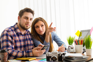 Two young creative designer colleagues using tablet at office