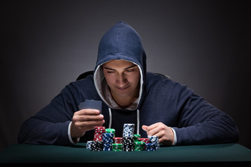 Young man wearing a hoodie with cards and chips gambling