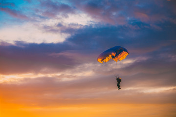 Skydiver On Colorful Parachute In Sunny Sky