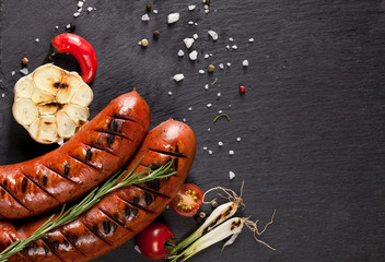 Grilled sausages on black background