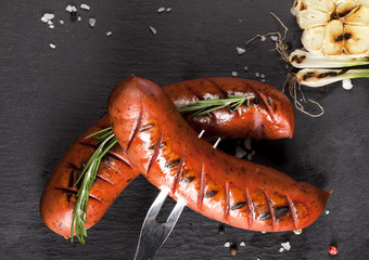 Grilled sausages on black background