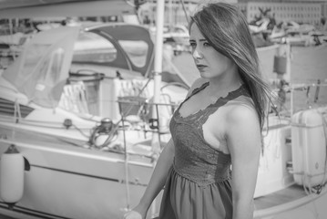 Melancholic woman in dress walking on marina