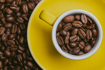Yellow small espresso cup with coffee seeds inside.