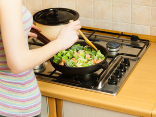 Woman cooking stir fry frozen vegetable on pan