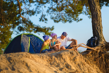 Fototapeta premium Happy family with backpack and tent looks into the distance