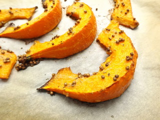 Baked pumpkin with coriander on a baking sheet
