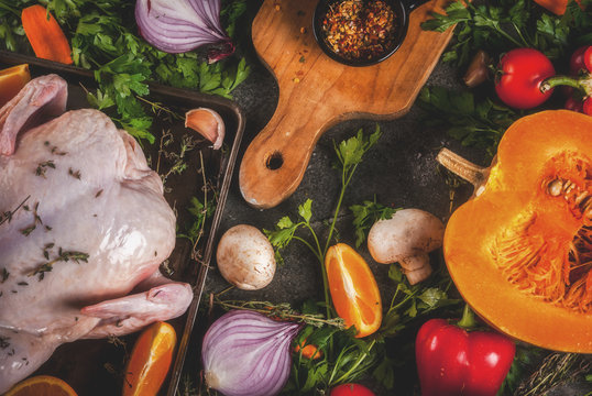 Cooking dinner for christmas, Thanksgiving. Traditional autumn ingredients are vegetables, pumpkin, mushrooms, chicken or turkey, fresh herbs, spices. On a dark table, Top view copy space