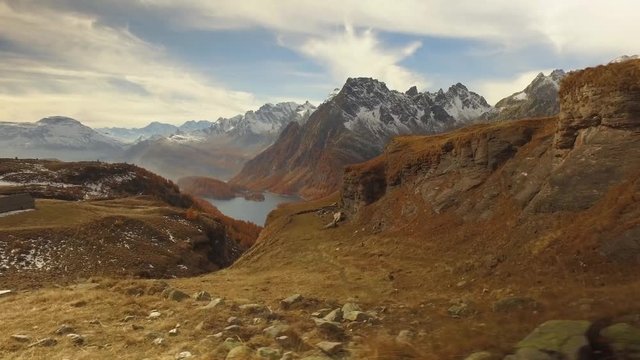 side POV walking on fall discovering woods, valley lake and snowy mounts.Sunny autumn day Hiking in colorful red forest wild nature mountain outdoors.Alps Devero.4k point of view establishing video
