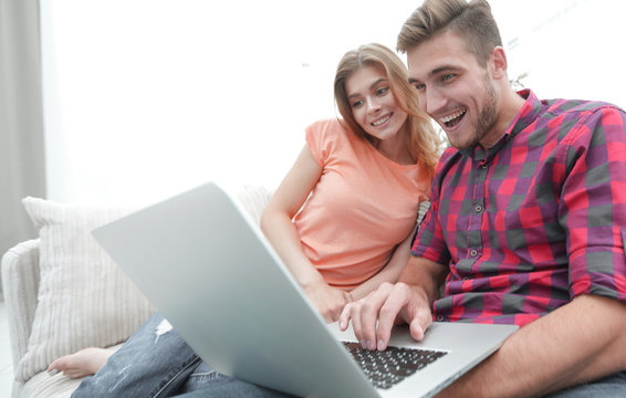 Happy modern couple surfing the net and working on laptop at home