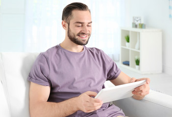 Young man searching information using tablet at home