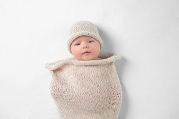 Cute newborn baby in knitted cocoon on white background
