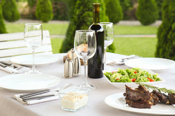 Delicious steak with wine on festive table outdoors
