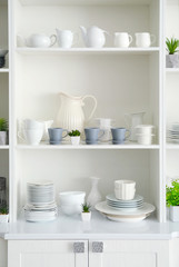 Obraz na płótnie Canvas White storage stand with ceramic dishware in kitchen