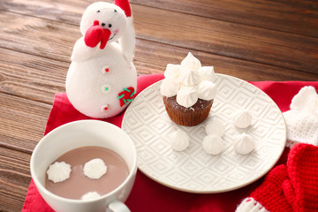 Composition with snowman toy, cup of hot cocoa and cupcake with marshmallows on table