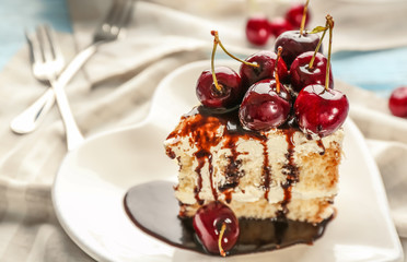 Heart shaped plate with piece of delicious cherry cake on table