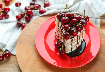 Plate with piece of delicious cherry cake on table