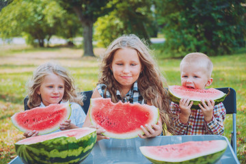 Big family with children eating watermelon.