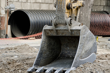 Large excavator bucket, trumpet in the background. Replacement of pipes