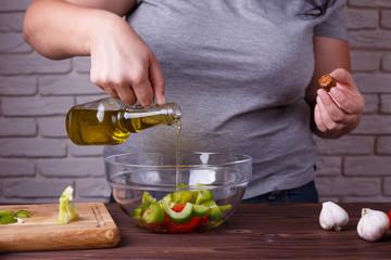Dieting, healthy low calorie food, useful fats, weight losing concept. Overweight woman pouring olive oil on salad in a bowl