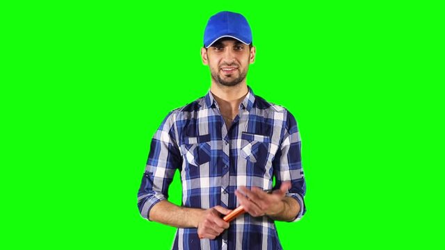 Male Caucasian plumber holding a wrench and smiling at the camera while standing against green screen background
