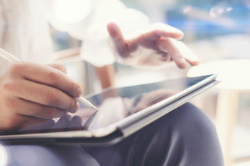 Closeup view of man holding tablet on hand and using electronic pen while working at office.Pointing tablet screen.Blurred background.Horizontal.