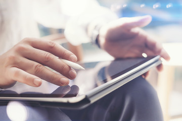 Closeup view of man holding digital tablet on hand and using electronic pen while working at...