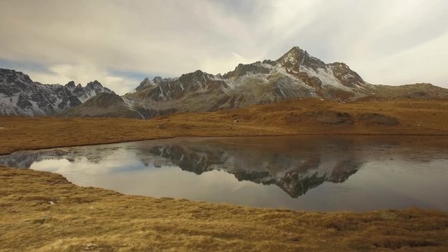 side POV walking on fall valley lake and snowy mounts approaching sunset.Sunny autumn day Hiking in colorful red forest wild nature mountain outdoors.Alps Devero.4k point of view establishing video
