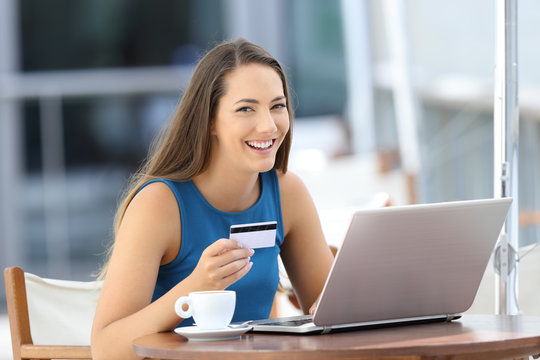 Happy buyer holding a credit card looking at you