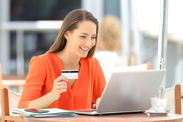 Woman in orange paying on line with a credit card