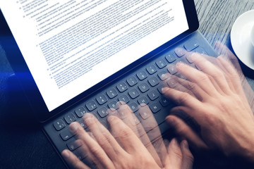 Closeup view of male hands quickly typing on electronic tablet keyboard-dock station. text information on device screen. Man working at office.Horizontal,cropp.